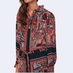 Κοντινό πλάνο του ίδιου φορέματος που αναδεικνύει το έντονο εμπριμέ μοτίβο σε κόκκινες και μπλε αποχρώσεις, τον όρθιο γιακά με διακριτικό βολάν και το μπροστινό κλείσιμο με κουμπιά. Φαίνεται μέρος των μανικιών με λάστιχο στη μανσέτα και το δέσιμο της ζώνης στη μέση. Φόντο καθαρό, ανοιχτό γκρι.