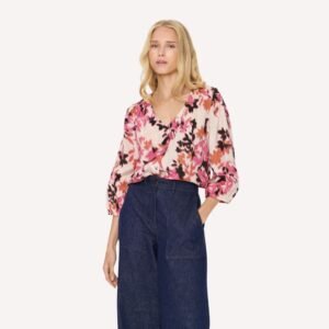Μοντέλο φοράει γυναικεία φλοράλ μπλούζα με V λαιμόκοψη και τζιν παντελόνι σε casual chic look.