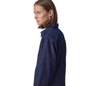 «Προφίλ γυναίκας που φορά denim πουκαμισοφόρεμα σε dark indigo χρώμα, με καθαρή ραφή και απλό γιακά, σε ουδέτερο φόντο.»