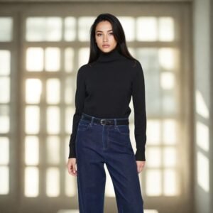 «Γυναίκα φοράει μαύρο πλεκτό ζιβάγκο με μακριά μανίκια και σκούρο μπλε ψηλόμεσο τζιν με ζώνη. Ποζάρει σε φωτεινό εσωτερικό χώρο με μεγάλα παράθυρα στο φόντο, δημιουργώντας κομψή και ζεστή ατμόσφαιρα που αναδεικνύει το διαχρονικό basic στυλ του ρούχου.»