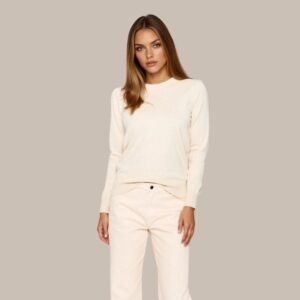 Γυναίκα μοντέλο φοράει εκρού πλεκτή μπλούζα με μακρύ μανίκι και στρογγυλή λαιμόκοψη, συνδυασμένη με εκρού παντελόνι σε ίσια γραμμή. Ουδέτερο φόντο στούντιο που αναδεικνύει το minimal στυλ του συνόλου