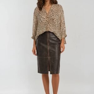 Γυναικείο σύνολο με λεοπάρ μπλούζα σε loose γραμμή και V λαιμόκοψη, συνδυασμένη με καφέ δερματίνη μίντι φούστα σε ίσια γραμμή με μπροστινό σκίσιμο. Το look ολοκληρώνεται με μαύρες γόβες, σε ουδέτερο studio φόντο που αναδεικνύει το κομψό και δυναμικό ύφος.