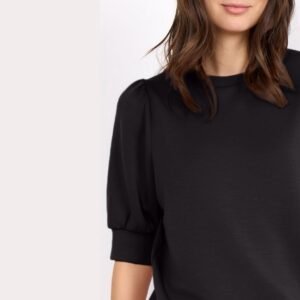 Κοντινό πλάνο μαύρης μπλούζας με φουσκωτά μανίκια ως τον αγκώνα που δείχνει το ύφασμα και τη λεπτομέρεια στα φουσκωτά μανίκια.