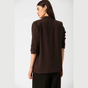 «Πλάγια οπίσθια λήψη μοντέλου που φορά το σοκολατί blazer Soaked in Luxury. Φαίνονται καθαρά οι λεπτομέρειες της πλάτης και των σουρωμένων μανικιών. Λευκό φόντο στούντιο.»