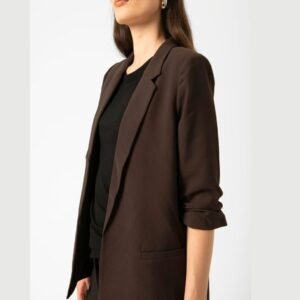 «Κοντινό στο πάνω μέρος του σοκολατί blazer Soaked in Luxury, αναδεικνύοντας το πέτο και τη μαλακή υφή του υφάσματος. Το μοντέλο φορά μαύρη μπλούζα. Ουδέτερο λευκό φόντο.»