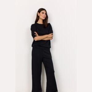 Μοντέλο με σταυρωμένα χέρια φοράει μαύρη μπλούζα με φουσκωτά μανίκια, σε φωτεινό λευκό φόντο.