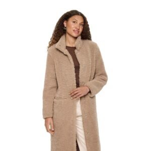 Γυναικείο μακρύ teddy παλτό σε μπεζ απόχρωση από απαλό συνθετικό ύφασμα, με όρθιο γιακά και άνετη εφαρμογή, φορεμένο με ανοιχτόχρωμο παντελόνι σε λευκό φόντο.