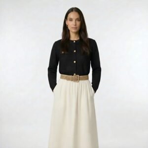 Γυναικεία μίντι φούστα σε εκρού απόχρωση με ελαστική μέση, συνδυασμένη με μαύρη πλεκτή ζακέτα με κουμπιά και ζώνη στη μέση, σε minimal studio φόντο.