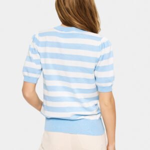Γυναικείο ριγέ πλεκτό top σε γαλάζιο και λευκό, πλάτη σε μοντέλο, λεπτή πλεκτή υφή με rib τελείωμα στη μέση και κοντά μανίκια, styling με μπεζ παντελόνι σε ουδέτερο studio φόντο.