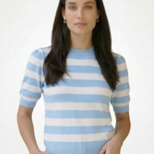 Γυναικείο ριγέ κοντομάνικο πλεκτό top σε απαλό γαλάζιο και λευκό με στρογγυλή λαιμόκοψη και rib τελείωμα, εφαρμοστή γραμμή, φορεμένο σε μοντέλο με μπεζ παντελόνι σε φωτεινό studio φόντο.