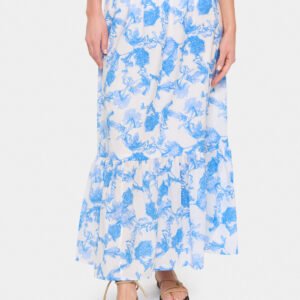 Μπροστινή λεπτομέρεια maxi φούστας με γαλάζιο floral print, βολάν στο τελείωμα και αέρια εφαρμογή, συνδυασμένη με flat σανδάλια.